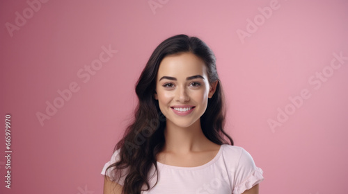 Stunning brunette in a pink T-shirt gracing the camera with a radiant smile, perfectly complemented by a pink backdrop.