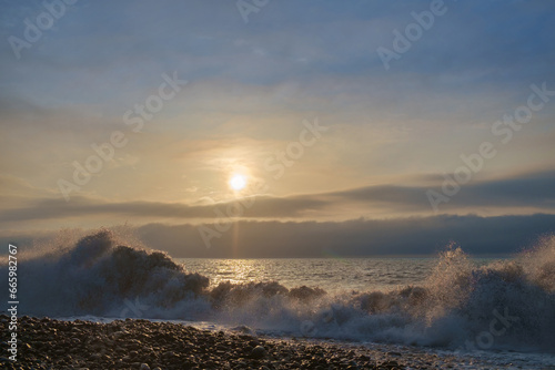 Waves on the rocky beach with cloudy sunset sky background