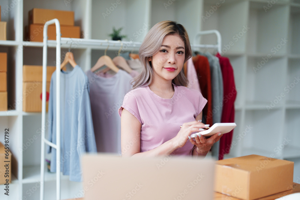 Portrait Of Asian Female Owner Of Fashion Store Checking Stock In Clothing Store With using notebook successful happy smile at small business, sme or ecommerce concepts Portrait Of Asian Female Owner Of Fashion Store Checking Stock In Clothing Store With using notebook successful happy smile at small business, sme or ecommerce concepts