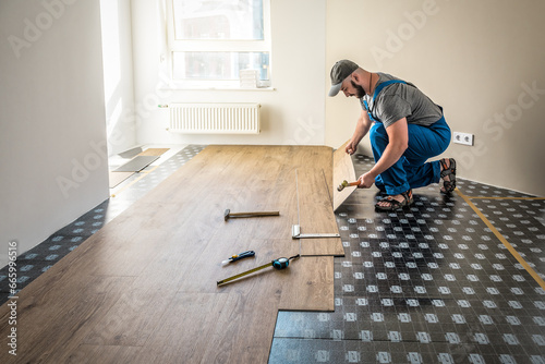 Professional worker joining vinyl floor covering at home renovation photo