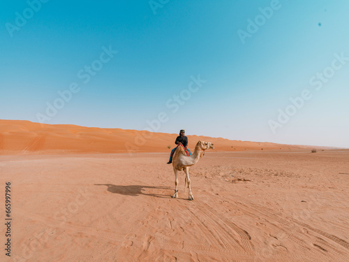 Man riding camel in the desert in Sultanate of Oman
