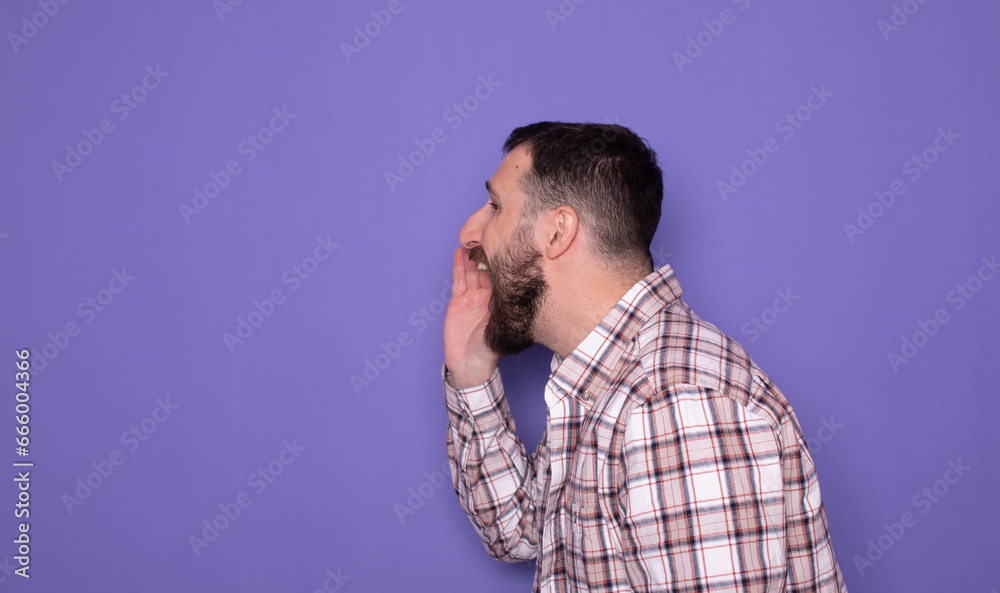 Attention! Close up portrait of bearded man holding hand near her open mouth isolated on purple background with copy space for text. Attention! Close up portrait of bearded man holding hand near her open mouth isolated on purple background with copy space for text.