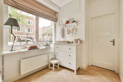 a room with wooden flooring and white cupboards in front of the window, there is a lamp on it