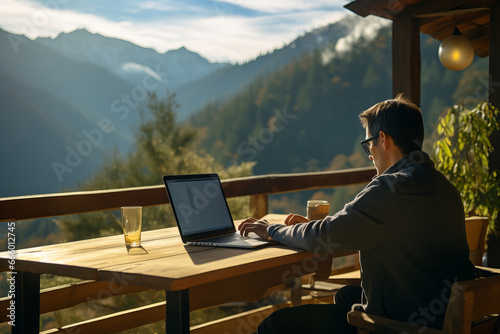 A man working comfortably on a laptop while enjoying a peaceful mountain view, showcasing the flexibility and choice of remote work environments © Mikhail
