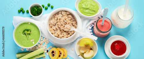 Bowls with healthy baby food on blue background.