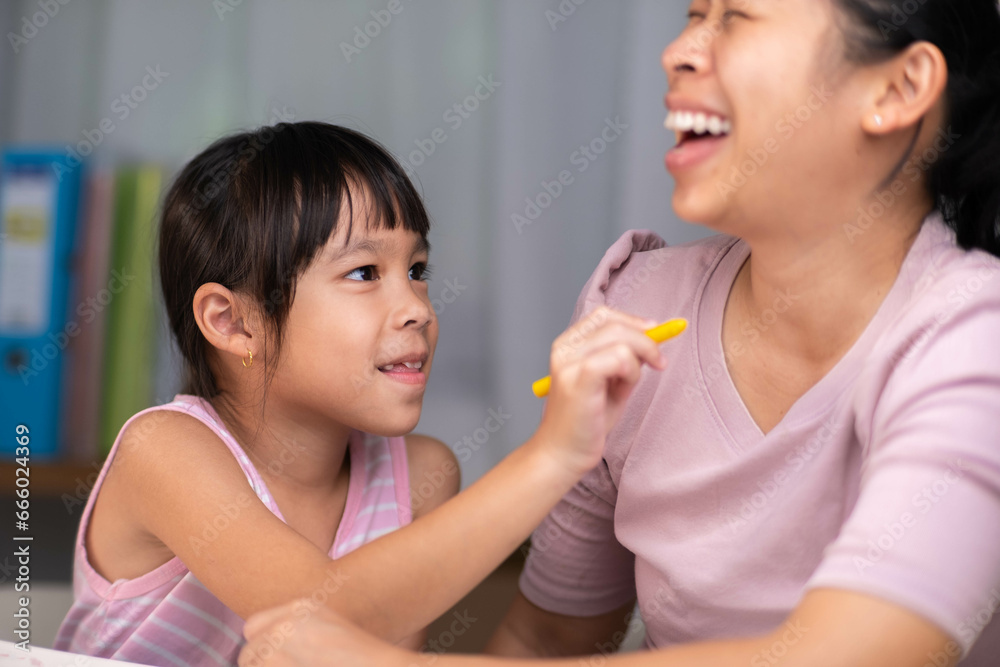Mother and daughter drawing together with crayons. Adult woman helps girl study or draw together at home in living room. Happy family. Mother and daughter drawing together with crayons. Adult woman helps girl study or draw together at home in living room. Happy family.
