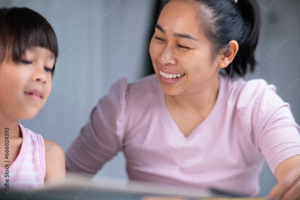 Mother and daughter drawing together with crayons. Adult woman helps girl study or draw together at home in living room. Happy family. Mother and daughter drawing together with crayons. Adult woman helps girl study or draw together at home in living room. Happy family.
