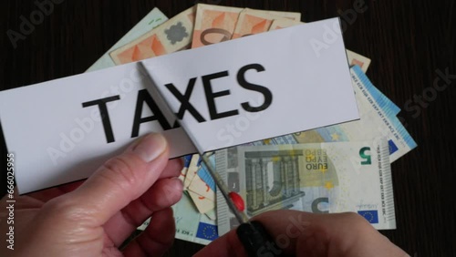 Wallpaper Mural the cutting paper with inscription taxes lies on top of a large pile of euro money on a dark wooden table, top view, tax reduction Torontodigital.ca