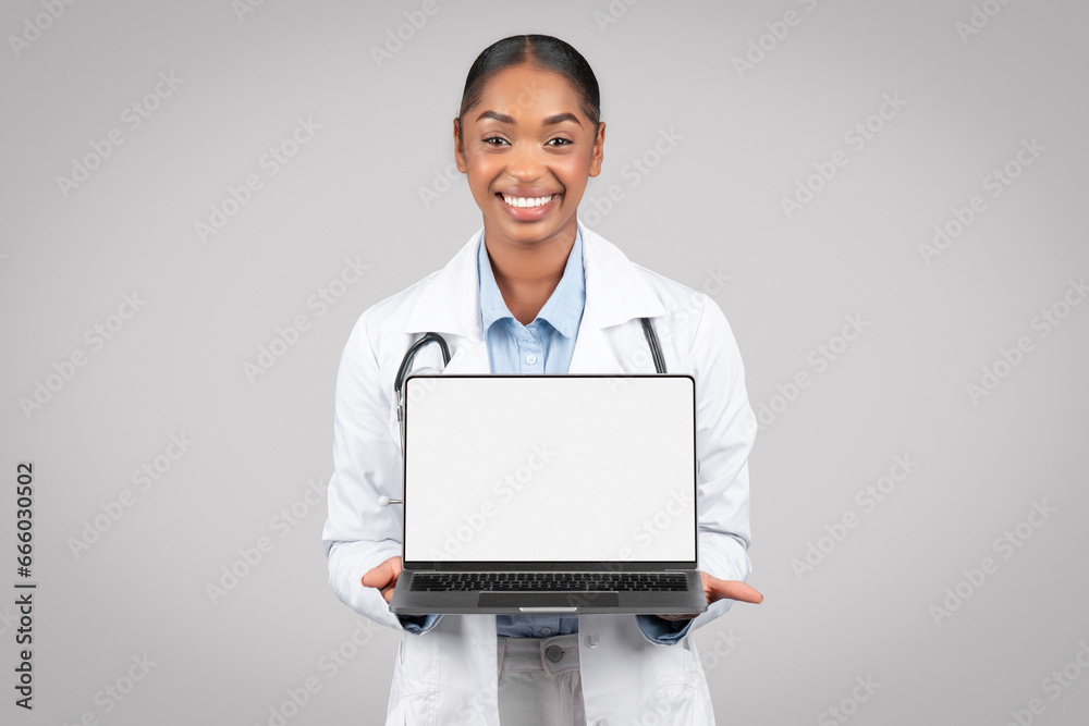 Smiling mature black woman doctor in white coat show tablet with empty screen Smiling mature black woman doctor in white coat show tablet with empty screen
