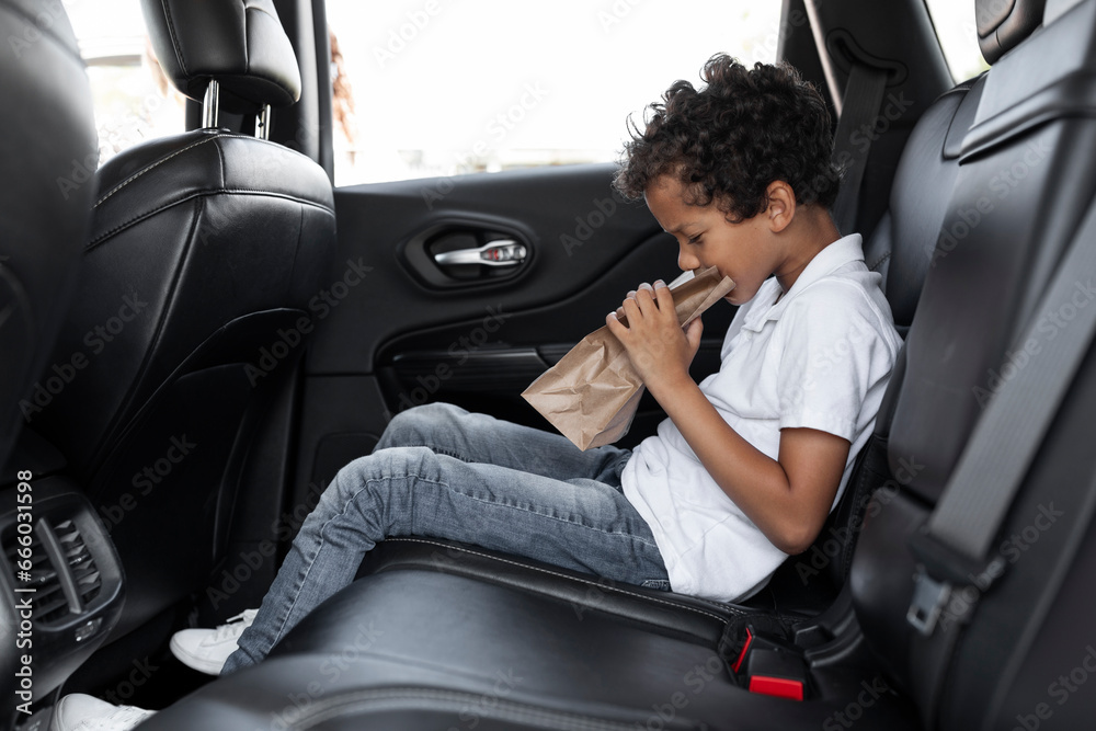 African american child in car backseat breathing in paper bag