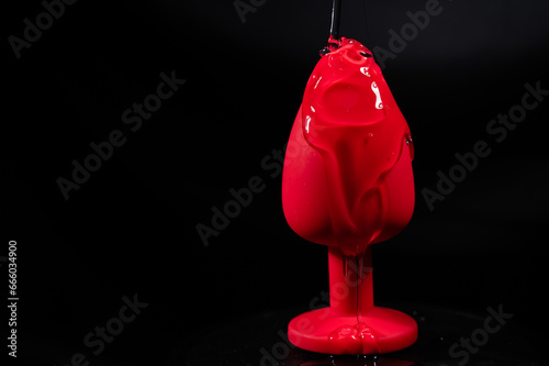 Intimate lubricant pours on a red anal plug on a black background. Copy space. 