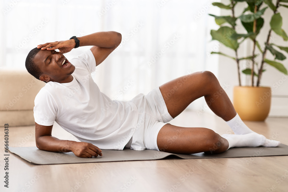 Obraz premium Tired black sportsman suffering from headache, have workout at home