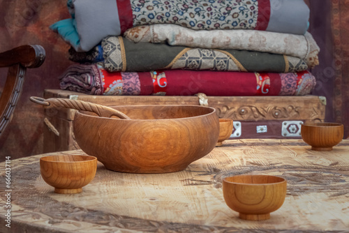 Traditional Asian wooden utensils for milk drinks stand on a low table against the background of a chest with blankets inside a nomadic home - a yurt. Close-up photo