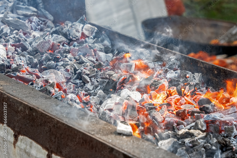 Fire and smoldering coals inside a metal grill for frying meat or vegetables outdoors. Preparing for a picnic Fire and smoldering coals inside a metal grill for frying meat or vegetables outdoors. Preparing for a picnic