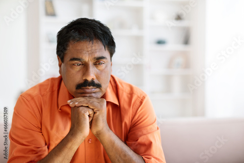 Canvas Print Closeup of depressed indian middle aged man sitting on couch