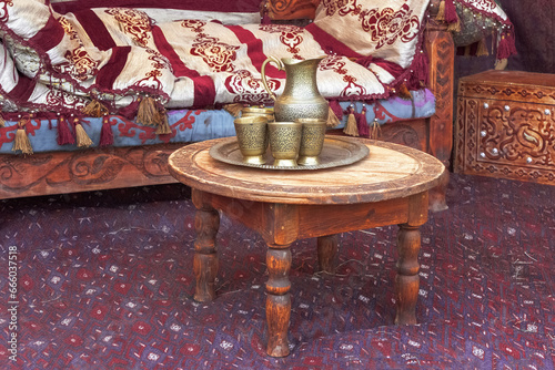 Traditional Asian silver jug and cups stand on an old wooden table in a yurt - the home of nomads.