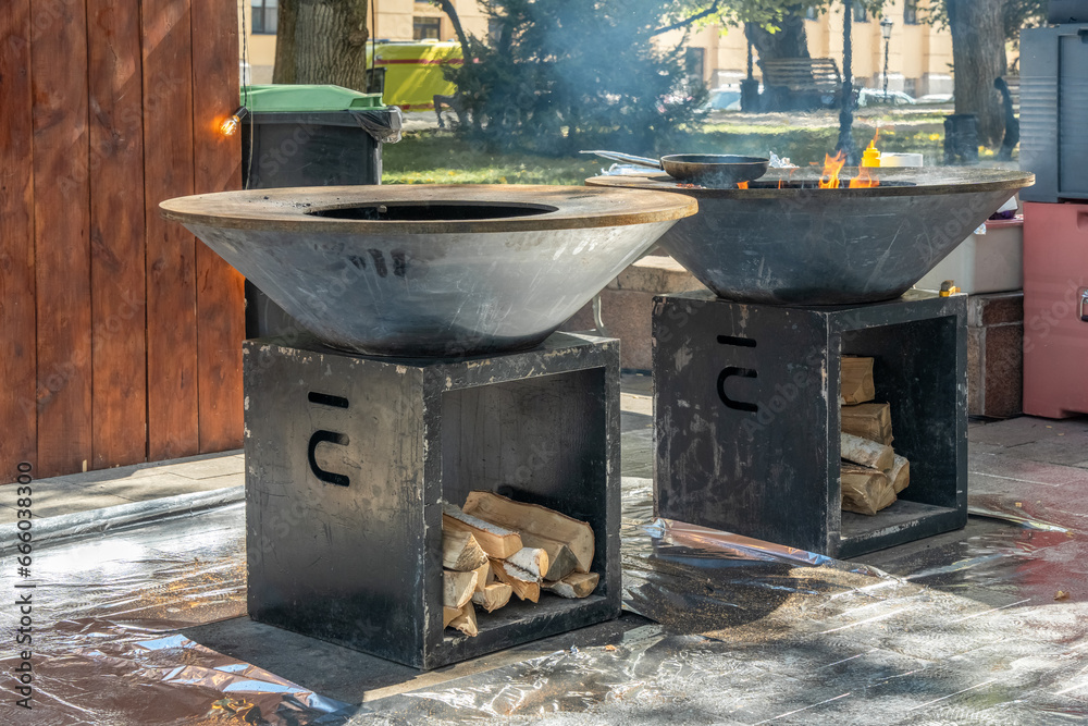 Wood-burning grill with a metal plate for frying meat and vegetables with a flame of fire. Street food Wood-burning grill with a metal plate for frying meat and vegetables with a flame of fire. Street food