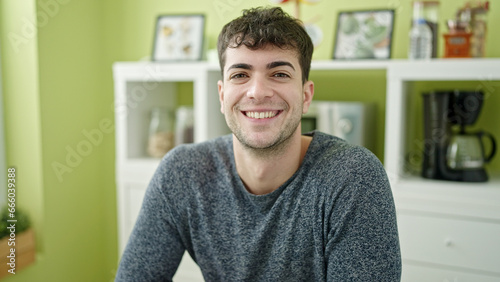 Young hispanic man smiling confident sitting on the table at dinning room