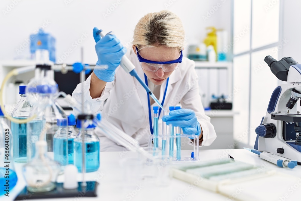 Young blonde woman scientist pouring liquid on test tube at laboratory Young blonde woman scientist pouring liquid on test tube at laboratory