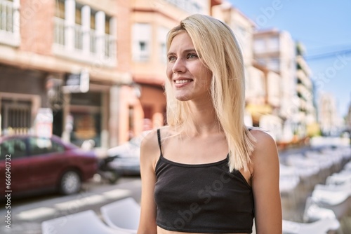 Young blonde woman smiling confident looking to the side at street