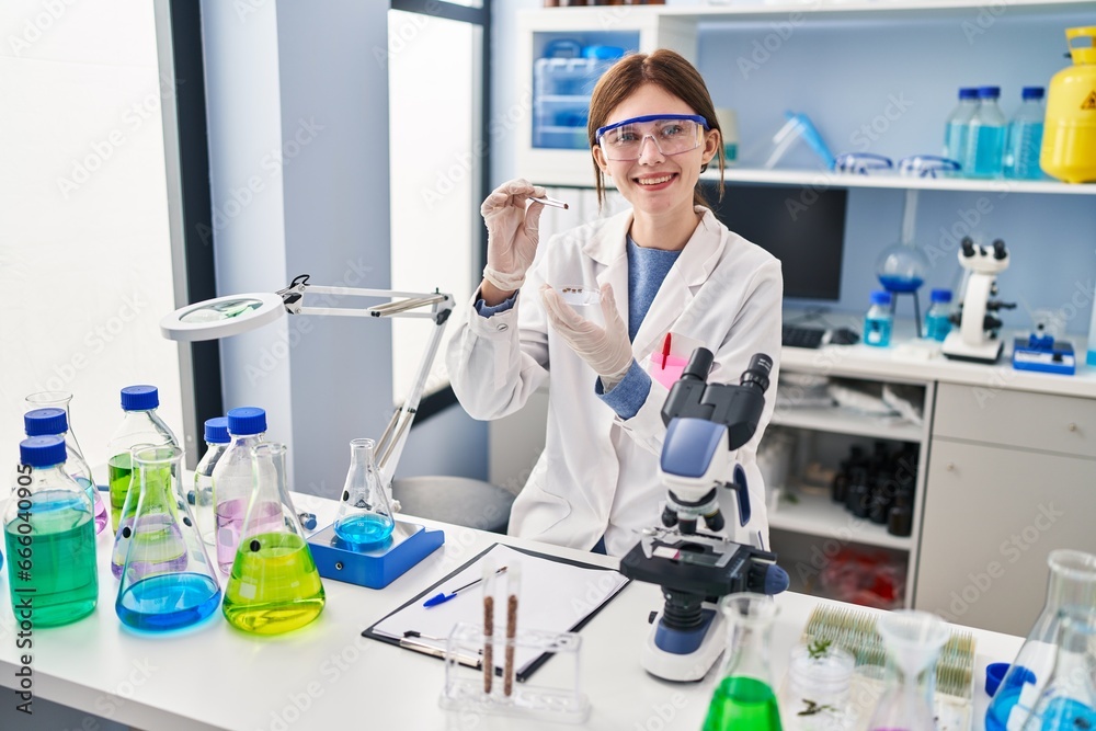 Young blonde woman scientist holding sample with tweezers at laboratory Young blonde woman scientist holding sample with tweezers at laboratory