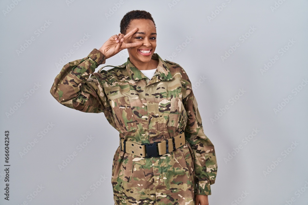 Beautiful african american woman wearing camouflage army uniform doing peace symbol with fingers over face, smiling cheerful showing victory