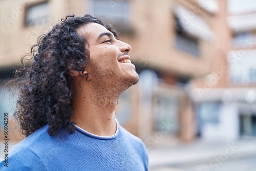 Young latin man smiling confident looking to the sky at street