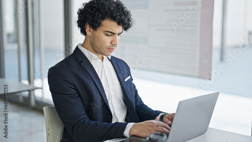 Young latin man business worker using laptop at office