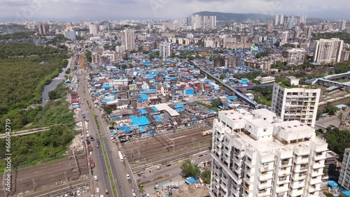 Aerial view of Mumbai city over Dharavi which is Asia's largest slum with local railway trains passing as city scape of Mumbai is revealed. Drone shot of Indian city over slum area with railways train
