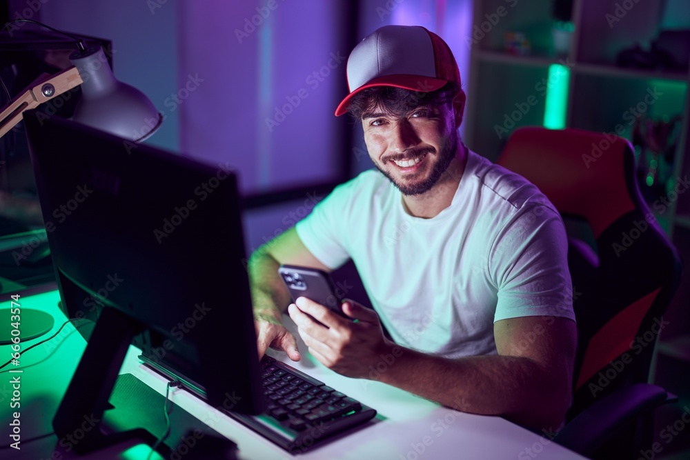 Young hispanic man streamer using computer and smarpthone at gamin room Young hispanic man streamer using computer and smarpthone at gamin room
