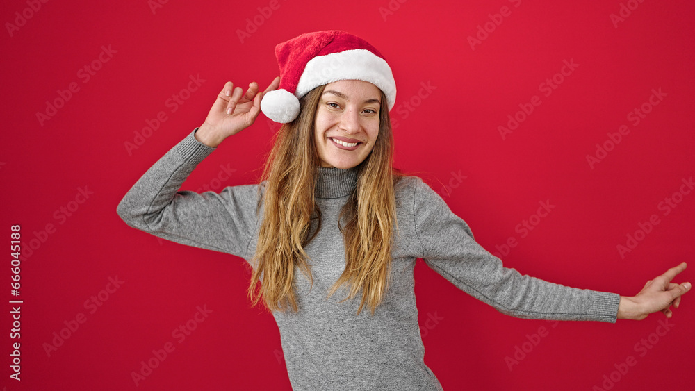 Young caucasian woman smiling confident wearing christmas hat dancing over isolated red background Young caucasian woman smiling confident wearing christmas hat dancing over isolated red background