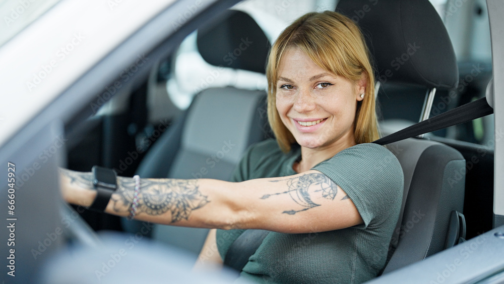 Young blonde woman smiling confident driving car at street