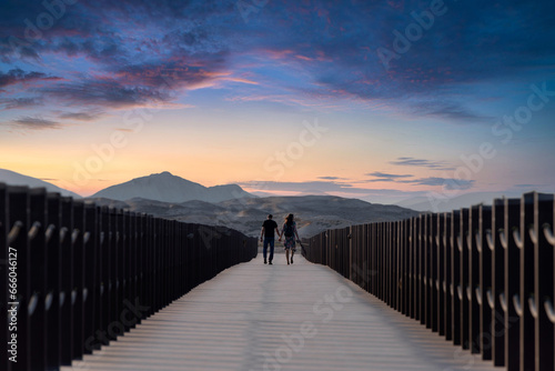 young Couple walking togathar back view on the wood bridge thakira purple island Qatar. No face