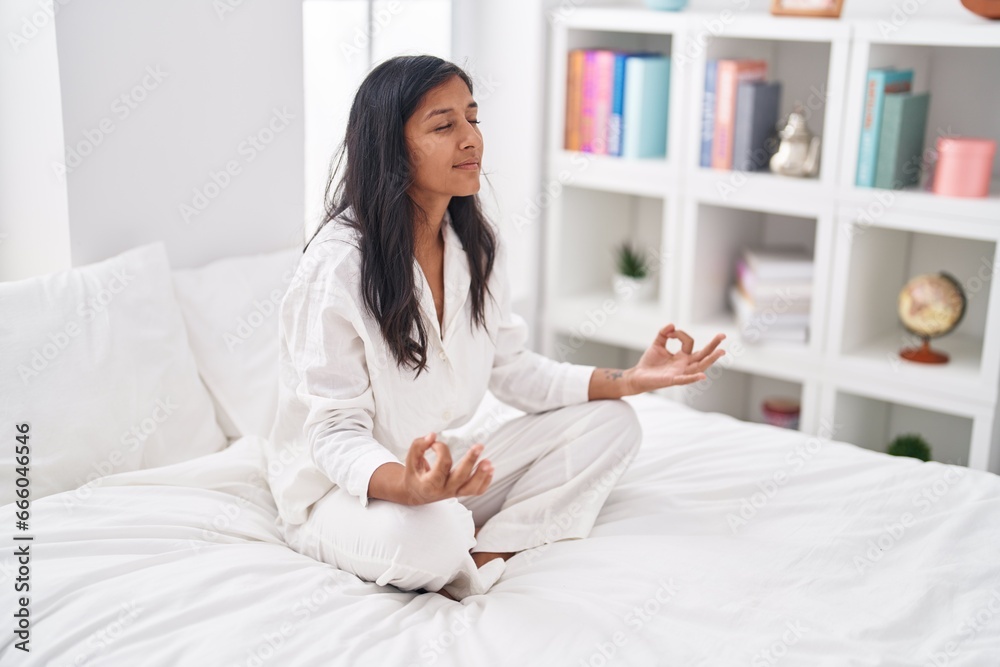 Young beautiful hispanic woman doing yoga exercise sitting on bed at bedroom Young beautiful hispanic woman doing yoga exercise sitting on bed at bedroom
