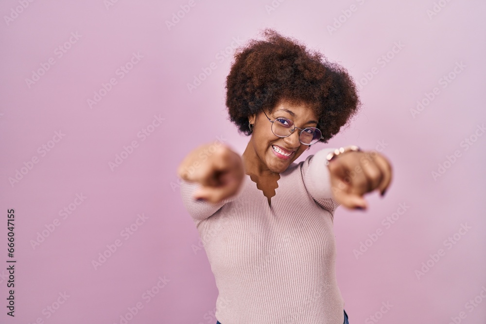 Young african american woman standing over pink background pointing to you and the camera with fingers, smiling positive and cheerful
