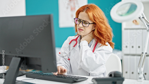 Young redhead woman doctor stressed working at clinic