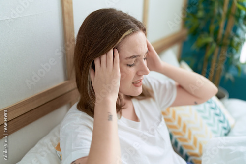 Young caucasian woman stressed sitting on bed at bedroom