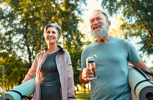 Portrait of two active sporty bright senior athletes holding exercise mats and walking outdoors in the park. Active old age. A walk, on the way to training. photo