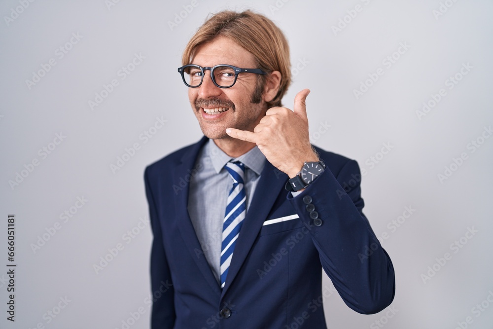 Caucasian man with mustache wearing business clothes smiling doing phone gesture with hand and fingers like talking on the telephone. communicating concepts.