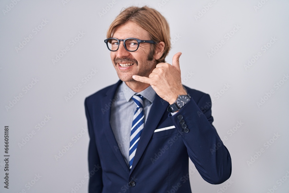 Caucasian man with mustache wearing business clothes smiling doing phone gesture with hand and fingers like talking on the telephone. communicating concepts. Caucasian man with mustache wearing business clothes smiling doing phone gesture with hand and fingers like talking on the telephone. communicating concepts.