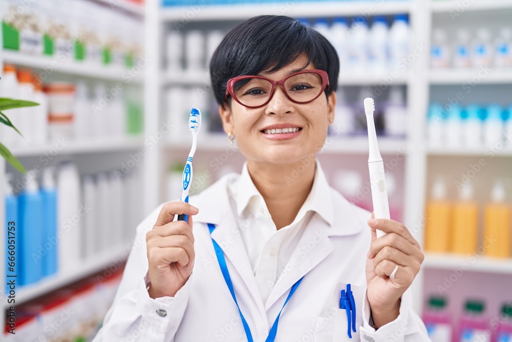 Young asian woman with short hair doing toothbrush comparative at pharmacy smiling with a happy and cool smile on face. showing teeth.