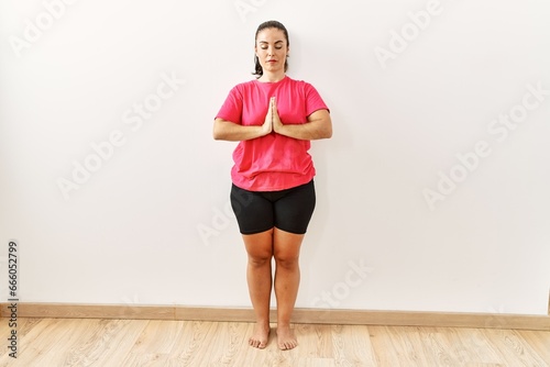 Young beautiful hispanic woman training yoga at sport center