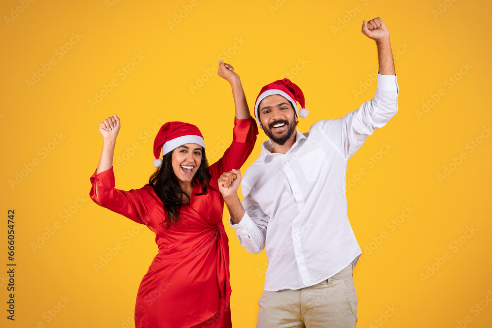 Cheerful latin man and woman in Santa hats, celebrating holiday with raised hands, festive cheer and excitement, dance Cheerful latin man and woman in Santa hats, celebrating holiday with raised hands, festive cheer and excitement, dance