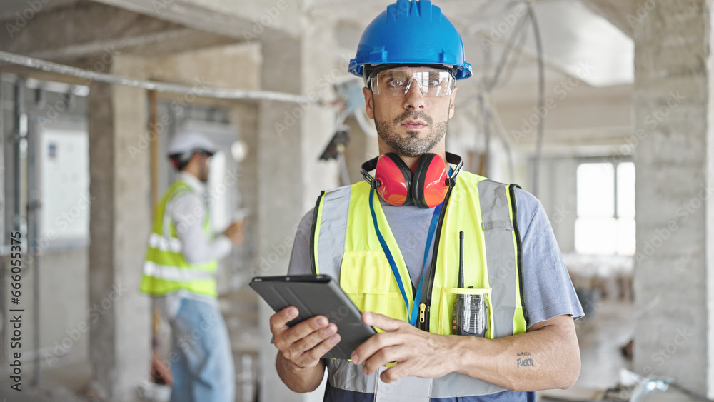 Two men builders using touchpad at construction site Two men builders using touchpad at construction site