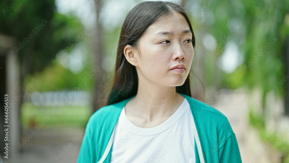 Young chinese woman looking to the side with serious expression at park Young chinese woman looking to the side with serious expression at park