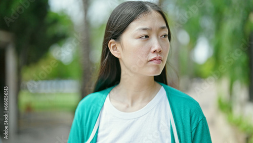 Young chinese woman looking to the side with serious expression at park © Krakenimages.com