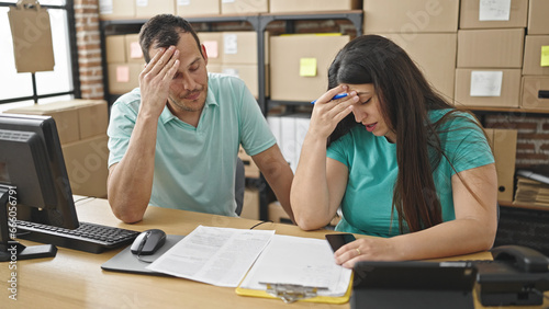 Two coworkers talking reading document worried at ecommerce office