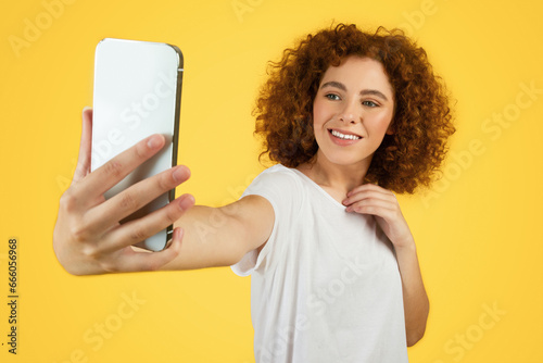 Cheerful teen woman student takes selfie on smartphone, enjoy spare time, video blog