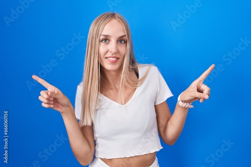Young caucasian woman standing over blue background smiling confident pointing with fingers to different directions. copy space for advertisement