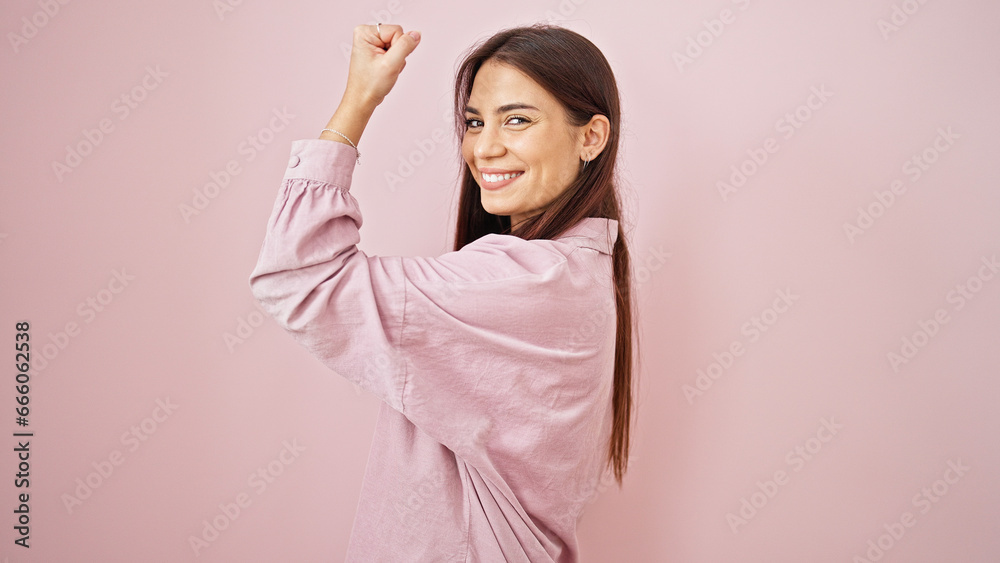 Young beautiful hispanic woman smiling confident doing strong gesture with arm over isolated pink background Young beautiful hispanic woman smiling confident doing strong gesture with arm over isolated pink background